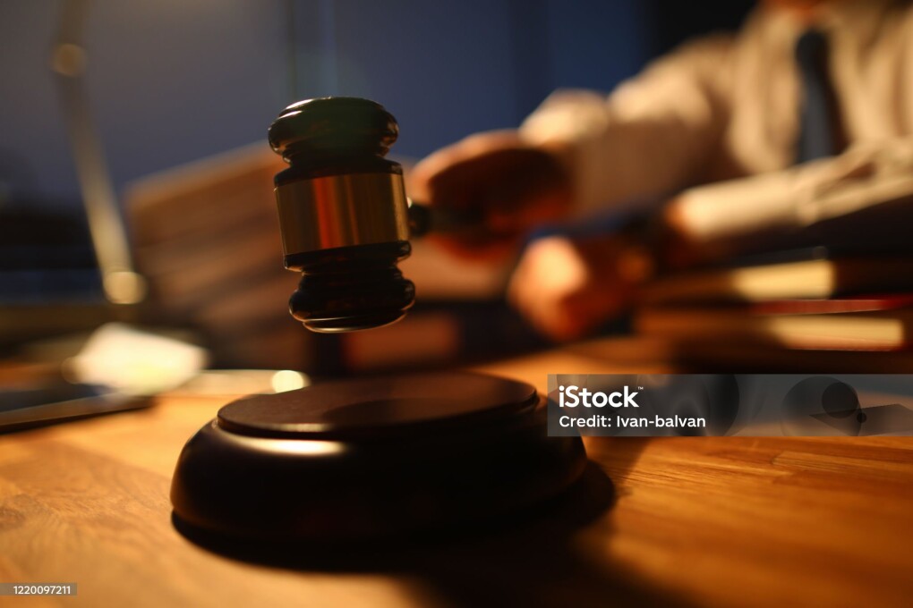 Focus on judge utility on wooden table used to maintain order and pronounce a verdict in courtroom in front of many people. Rule of law and strict court concept