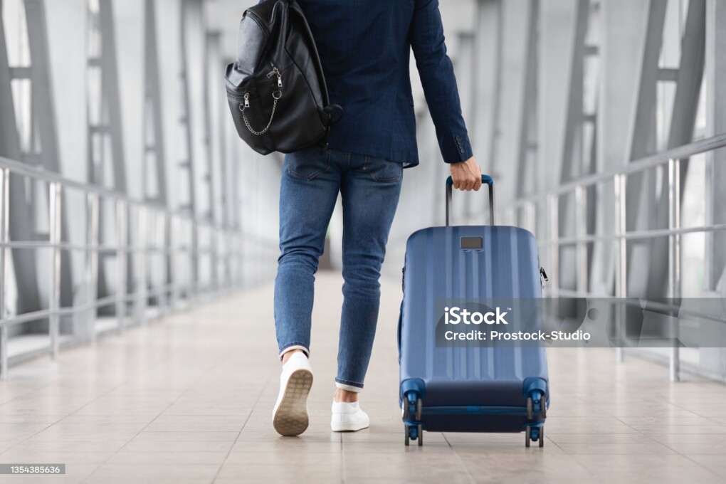 Unrecognizable Man With Bag And Suitcase Walking In Airport Terminal, Rear View Of Young Male On His Way To Flight Boarding Gate, Ready For Business Travel Or Vacation Journey, Cropped, Copy Space