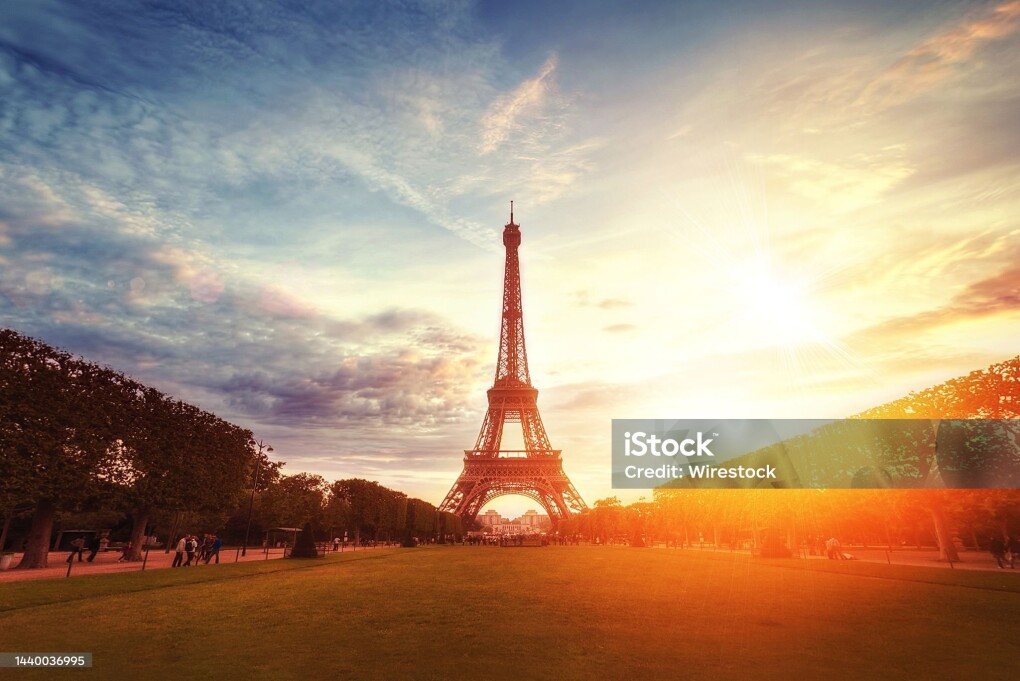 A beautiful wide shot of the famous Eifel tower under the breathtaking cloudy sky at sunrise in Paris