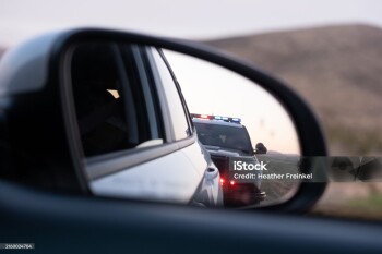 View from the passenger seat rear view mirror of getting pulled over by a police car