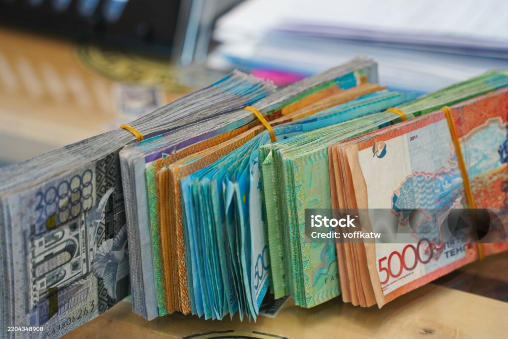 Banknotes of Kazakhstani tenge of different denominations are on the table.
