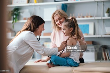 A friendly pediatrician performs a health examination for a happy young girl, observed by her caring mother. The image conveys family care, child health, and professional medical service.