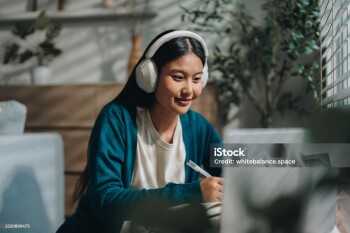 Woman enjoying her online class, attentively taking notes as she stays engaged and focused. With a sense of curiosity and dedication, she embraces the opportunity to learn from home and improve her knowledge