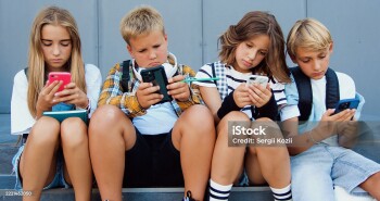 Group of teenage sad friends holding phones and browsing sitting on stairs near school building after lerning day. Happy positive teens friends texting on cellphones gadgets and talking.