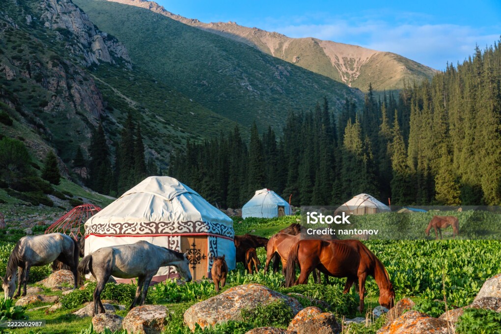 Kyrgyzstan iconic picture. Traditional Kyrgyz yurts with horses in a scenic mountains landscape. Altyn Arashan valley, Karakol city. Nomadic traditions