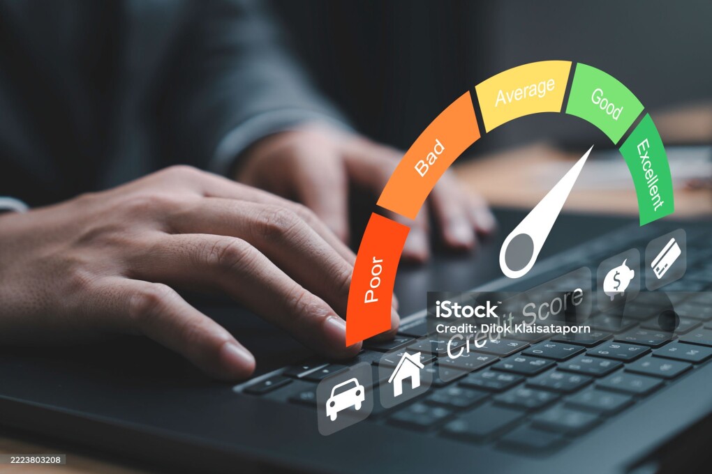 Close-up of hand typing on a laptop with a credit score gauge displayed. The gauge indicates varying levels of credit quality from poor to excellent for highlighting the importance of financial health