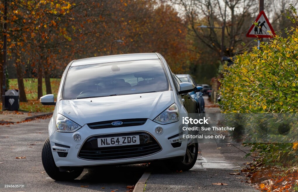 Milton Keynes,Bucks,UK -Nov. 8th 2025: Line of cars parked on the pavement next to a road sign warning of frail and elderly pedestrians.