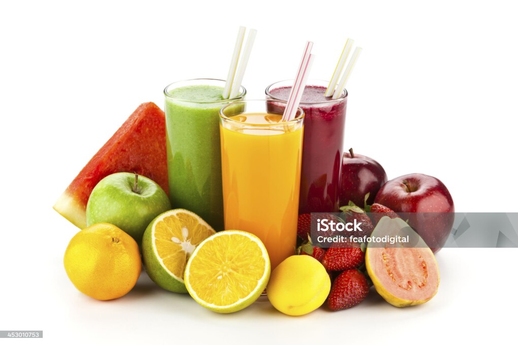 Three glasses of fruit juice are arranged in a triangle shape and surrounded by a variety of colorful fruits including oranges, strawberries, apples, watwrmelon slice, and guajava. There is an orange juice, strawberry juice and a green juice. The composition is isolated on white backdrop with natural shadow. Colors are very saturated. Picture taken with DSLR Canon EOS 5D MkII