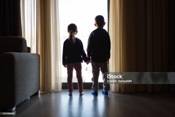Boy and girl from back, looking trough the window.
