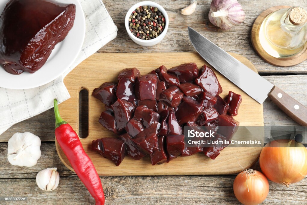 Cut raw beef liver and products on wooden table, flat lay