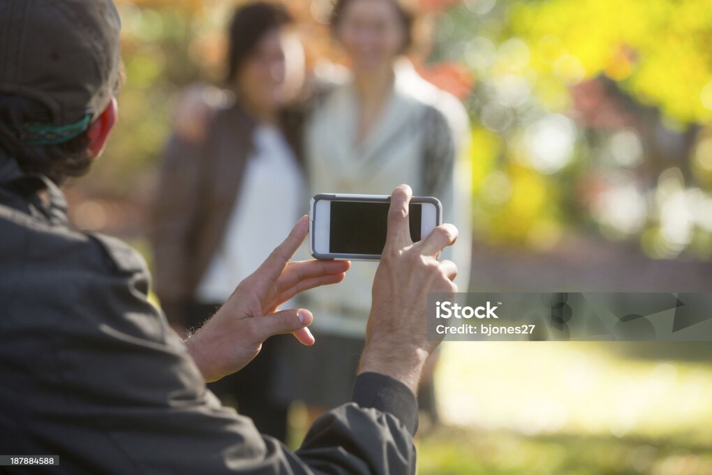 Young people hanging out, in the fall, taking pictures with thier smart phones