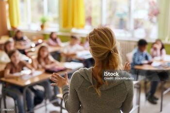 Rear view of a female teacher teaching her students during a class at elementary school.
