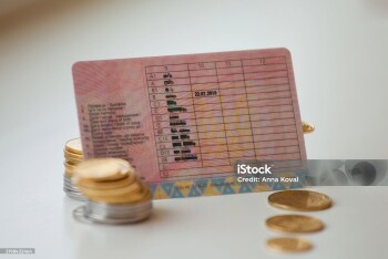 The photo shows a driver's license and stacks of coins next to it