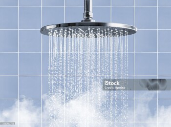 Rainfall shower head that creates a captivating water display accompanied by soothing steam on blue tiled wall background
