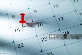 Red thumbtack on the 15th of calendar with light rays and shadow