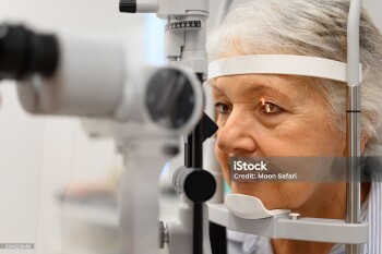 Close-up of mature woman undergoing eye examination with slit lamp for vision checkup at ophthalmology clinic