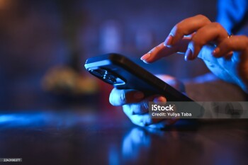 Woman's hands texting on a mobile phone with blue screen light in a dark room