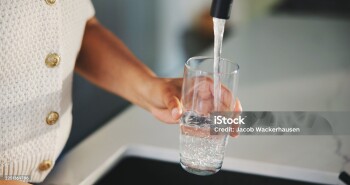 Glass, water and tap with hands of woman in kitchen for detox drinks, mineral hydration and health in home. Electrolytes, wellness and aqua with person for faucet, liquid or beverage in apartment