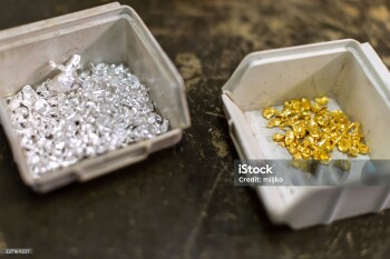 Close-up of boxes with multiple pieces of raw, pure gold and silver on a table.