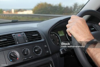 Man's hands on a steering wheel demonstrating the correct procedure for holding a steering wheel and car safety