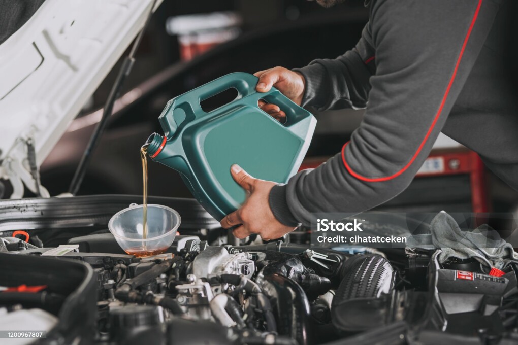 Pouring oil to car engine.