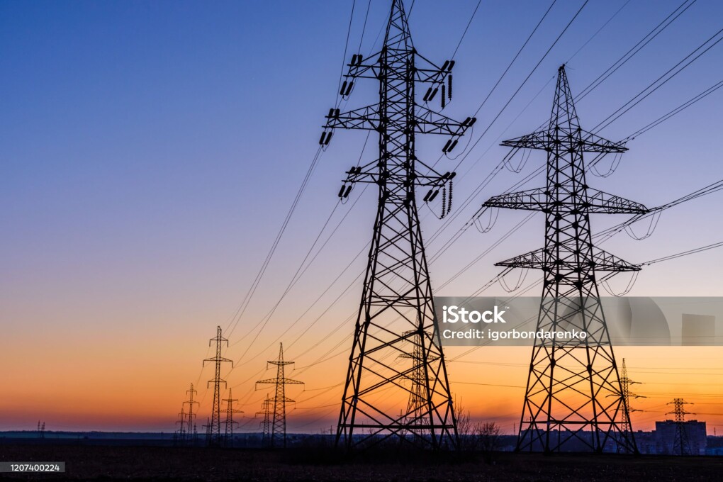 High voltage power line in field at sunset