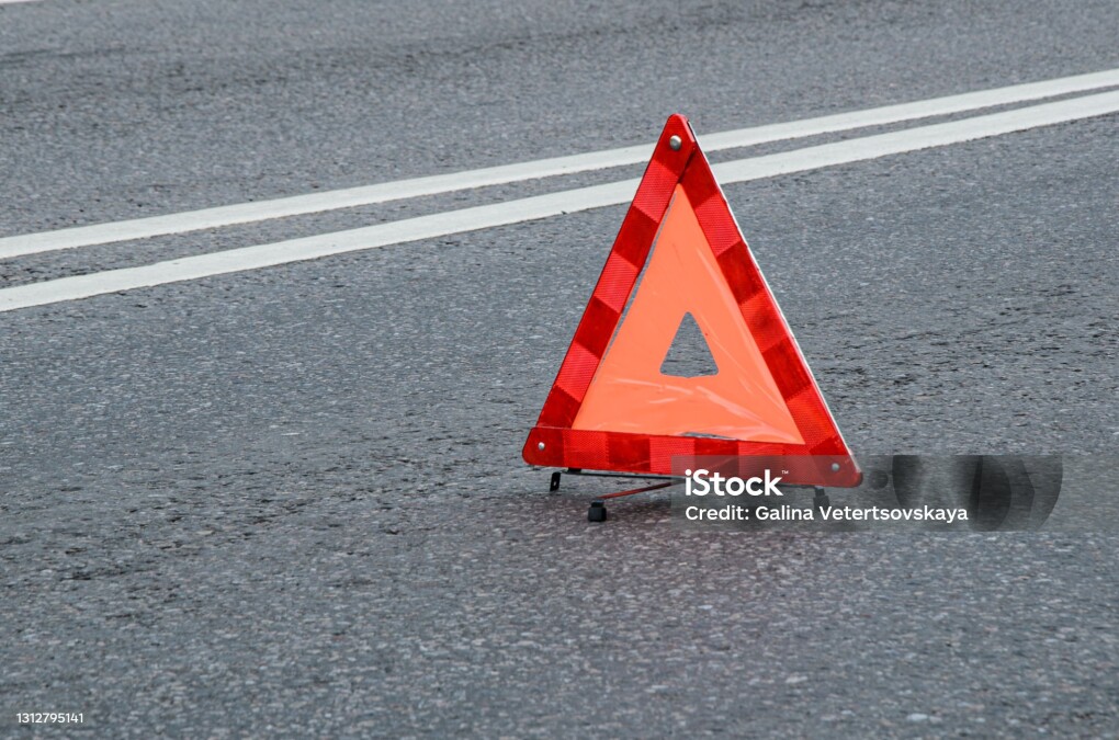 Red warning triangle on the carriageway with a double dividing strip. Traffic rules, traffic accidents, road safety.