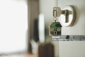 Open the door and door handle with a key and a keychain shaped house. Property investment and house mortgage financial real estate concept