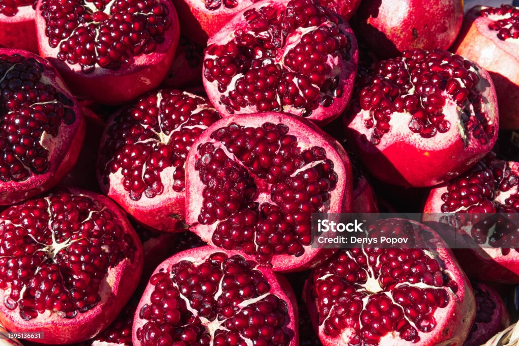 a lot of ripe red pomegranates with a cut off top, close-up background, space for an inscription. High quality photo