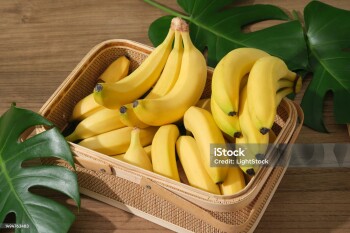 Bananas are arranged inside a bamboo basket decorated with some fresh green leaves. Banana (Musaceae) will protect the body from damage caused by the oxidation of free radicals