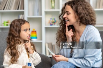 Speech therapy. Cute long-haired girl having speech therapy session with the doctor
