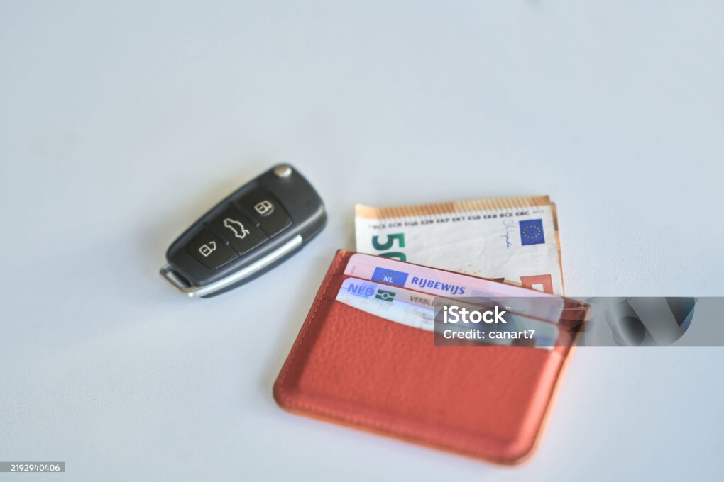 Car key, wallet with documents and 50 euro banknote on white table