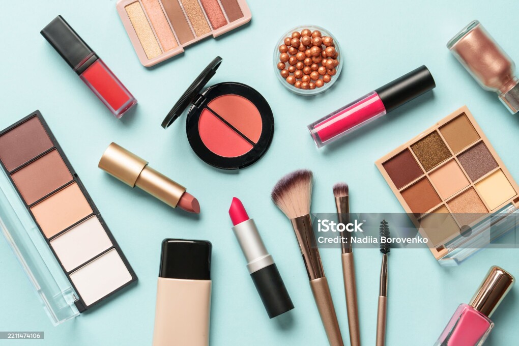 Beauty products on blue background. Cosmetic palette, brushes, cream and lipsticks. Top view.