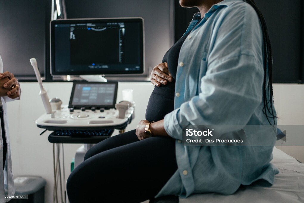 Pregnant woman holding her belly during a prenatal exam.