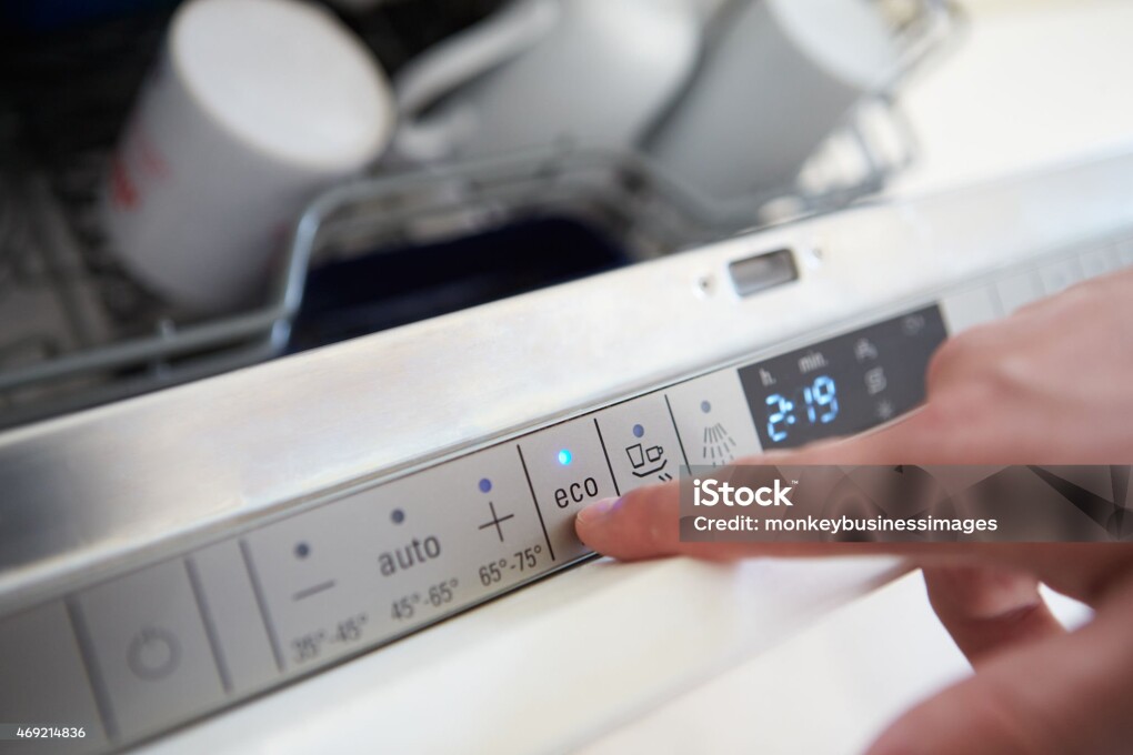 Close Up Of Man Setting Economy Cycle On Dishwasher