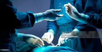 doctor and nurse medical team are performing surgical operation at emergency room in hospital. assistant hands out scissor and instruments to surgeons during operation.