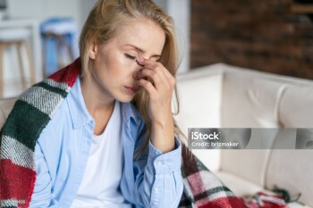 Fatigue and upset woman touching nose bridge feeling eye strain or headache, trying to relieve pain. Sick and exhausted female spending day at home. Depressed lady feeling weary dizzy