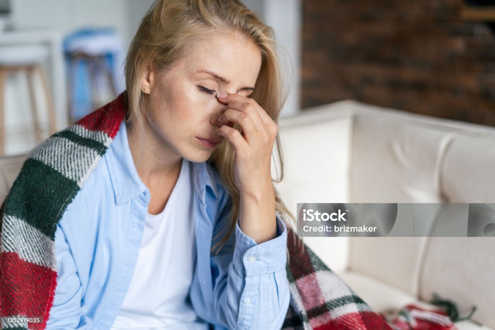 Fatigue and upset woman touching nose bridge feeling eye strain or headache, trying to relieve pain. Sick and exhausted female spending day at home. Depressed lady feeling weary dizzy