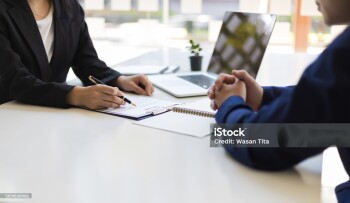 The manager is reading the resume and is interviewing the new employee. Negotiating business and signing a contract. Lawyer and legal advisor.