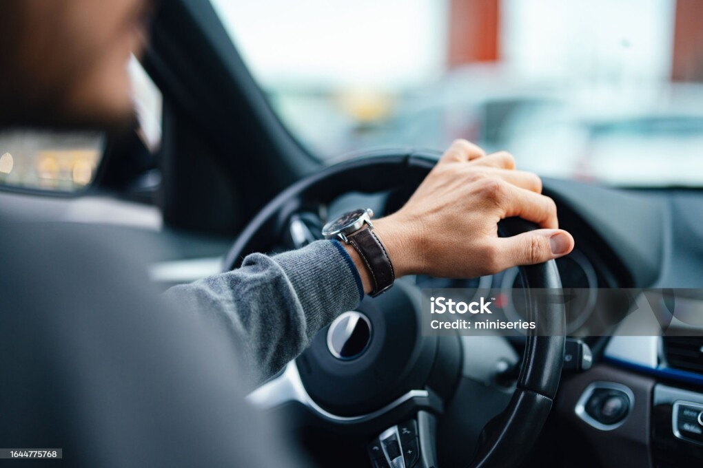 A close up view of an unrecognizable Caucasian male working as a taxi driver.