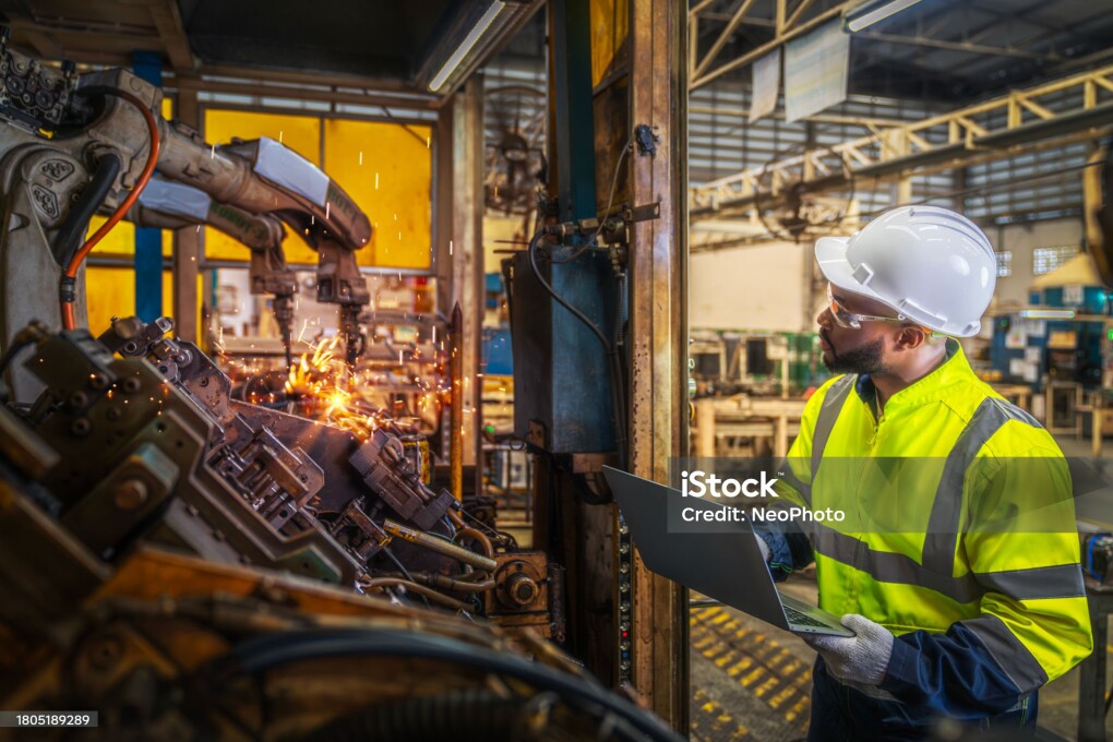 African american worker working in old united state factory in robot auto welding machine section and welding for assembly matal part, America