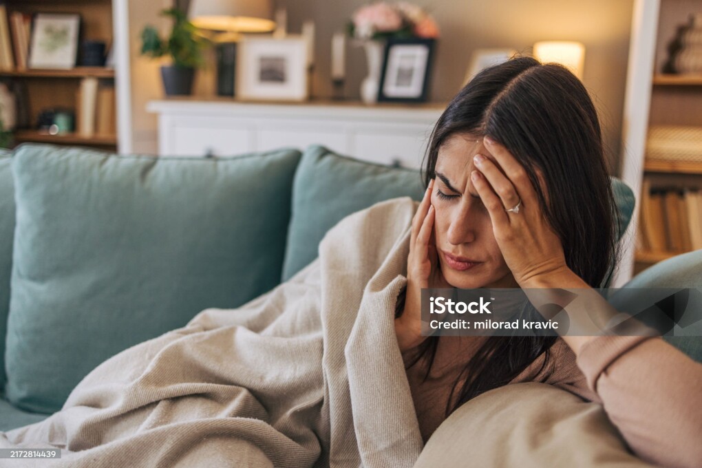 A young woman lying on the sofa in the living room, feeling sick.
