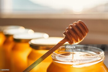 Honey dipper and open glass of honey.