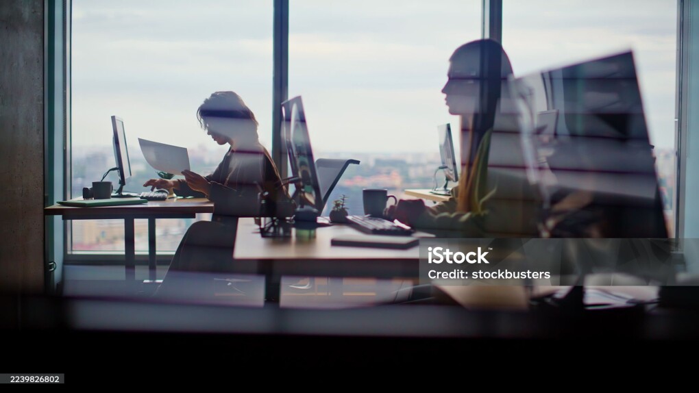 Busy corporate office silhouettes at cityscape window place closeup. Young people working computers feeling involved at creative agency. Men women writing emails typing keyboards together at coworking