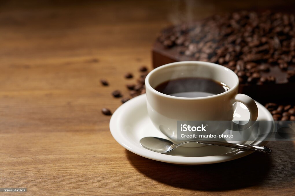 Cup of coffee with grains on wooden background