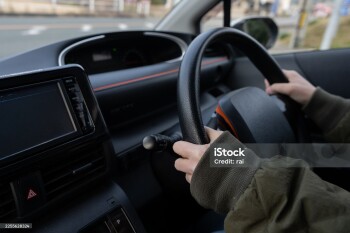 Hands of a person holding the steering wheel of a car
