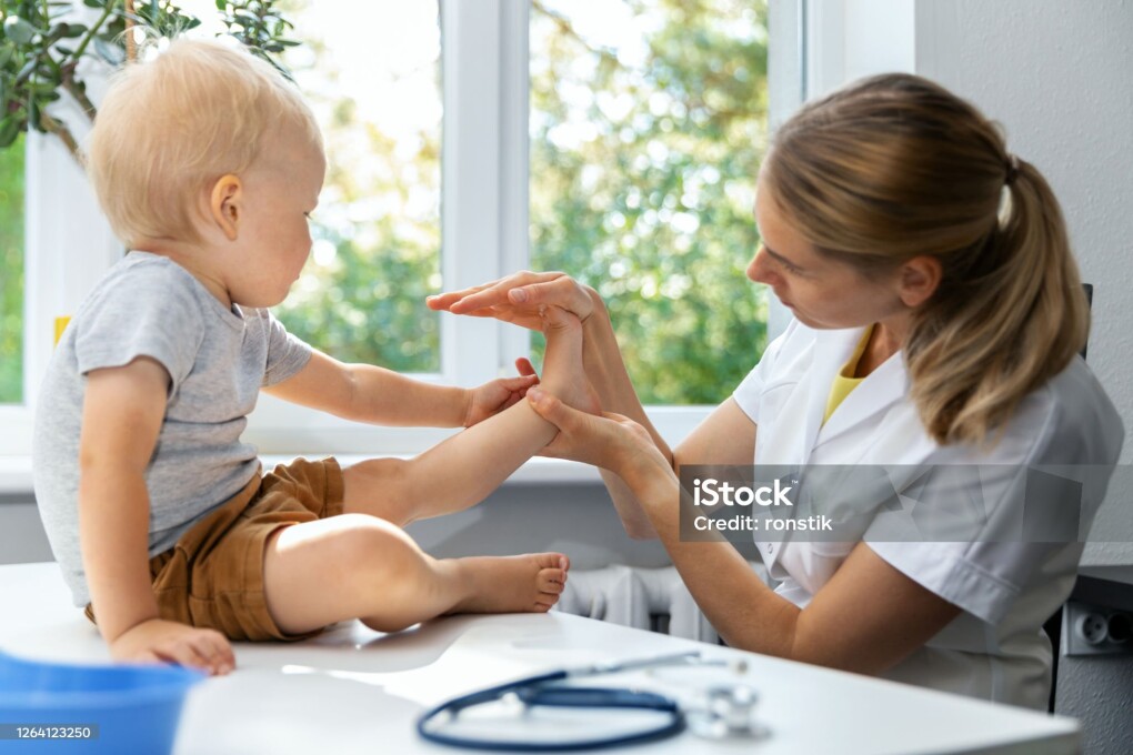 female orthopedist examining little child foot condition in clinic