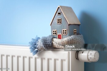 House model wrapped in scarf on radiator home winter heating and insulation background fuel and energy crisis concept