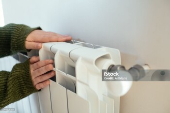 Young woman trying to warm near a radiator in winter, close-up