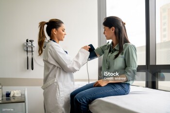 Doctor checking the blood pressure on a Latin American woman in a consultation - medical exam concepts